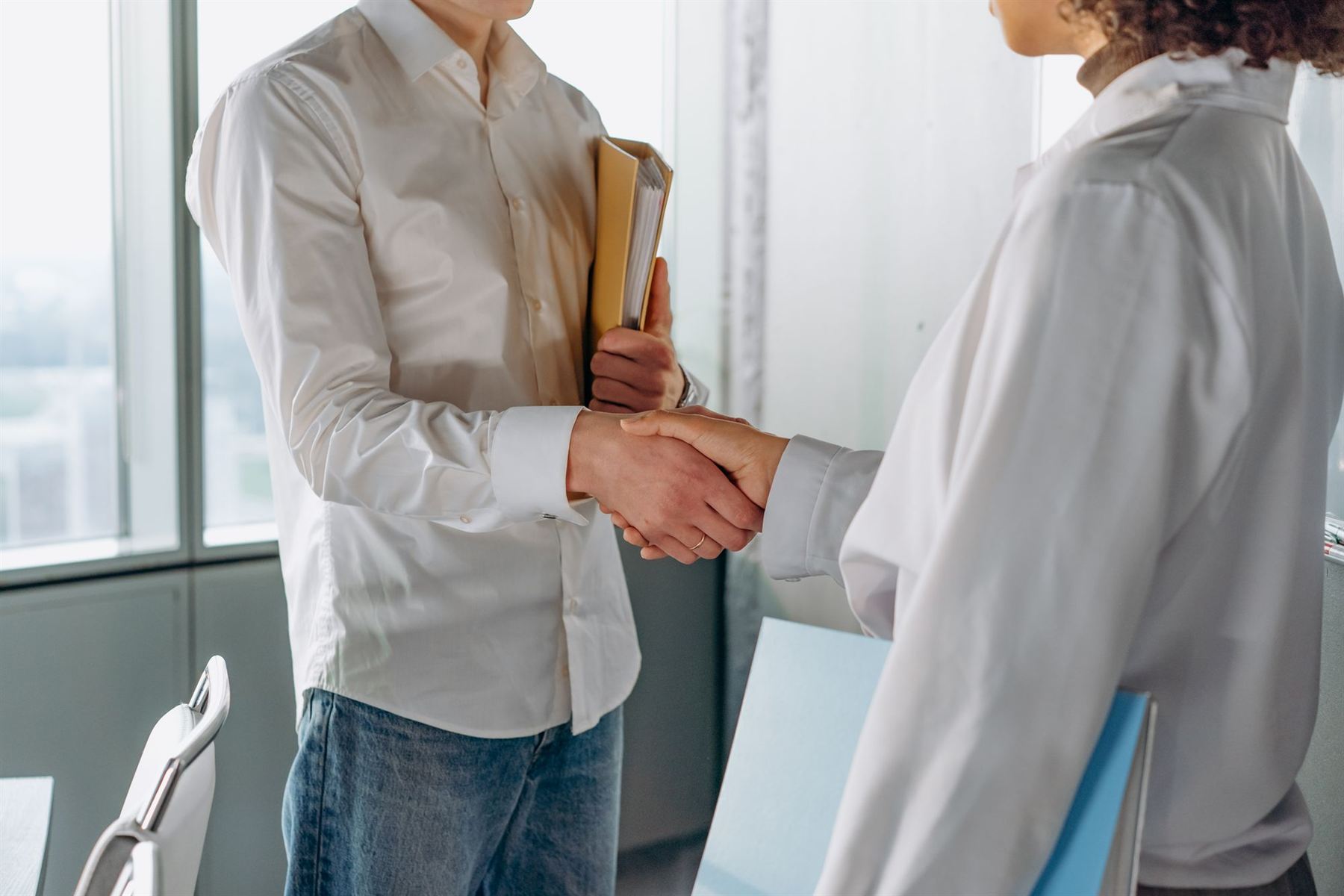 Two professionals shaking hands in a bright, modern office