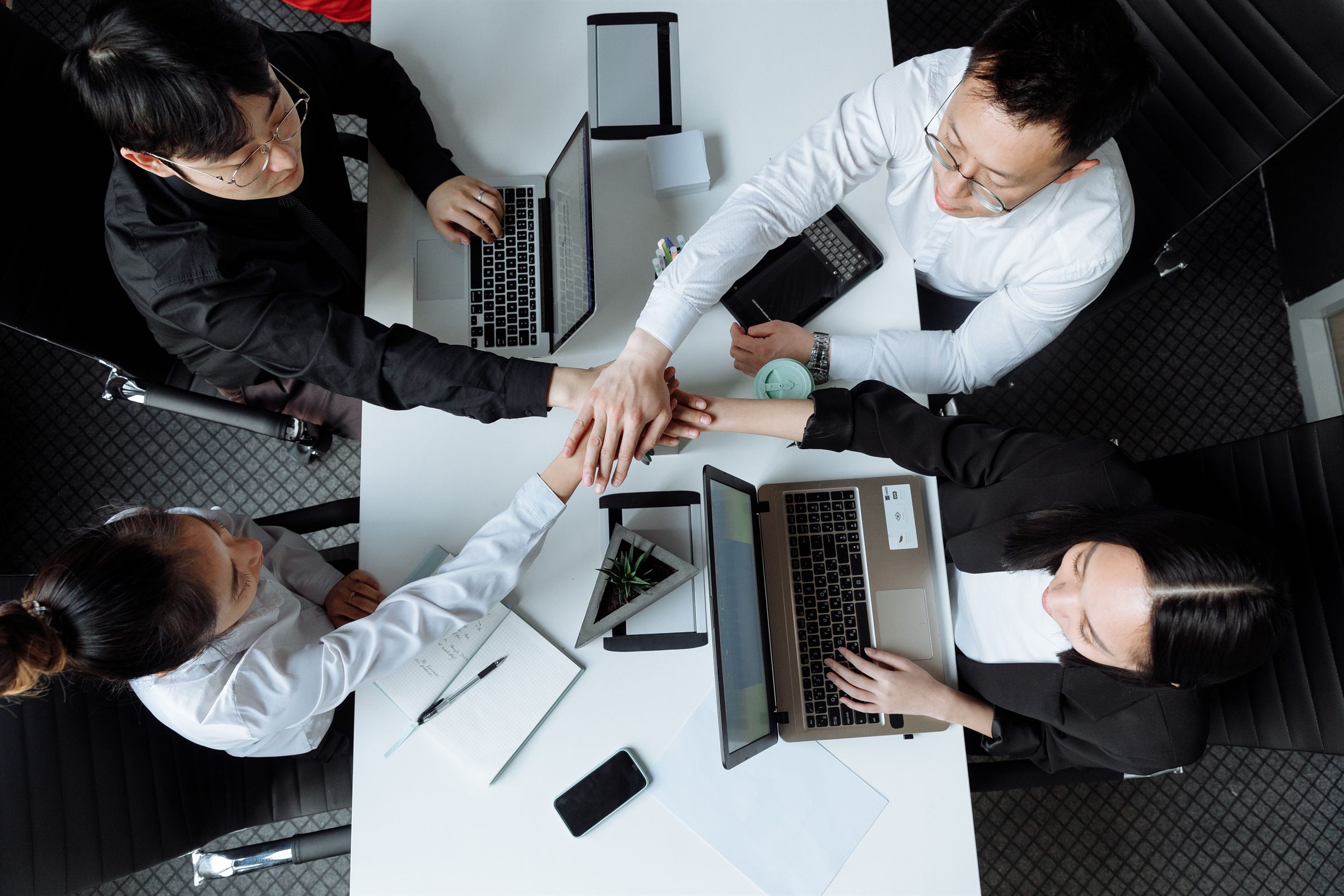 A business team joining hands over a meeting table