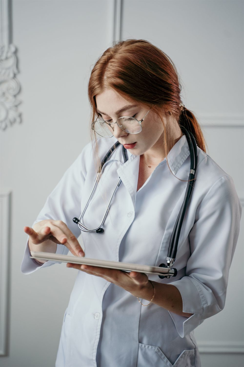 A doctor in a white coat reviewing notes on a tablet