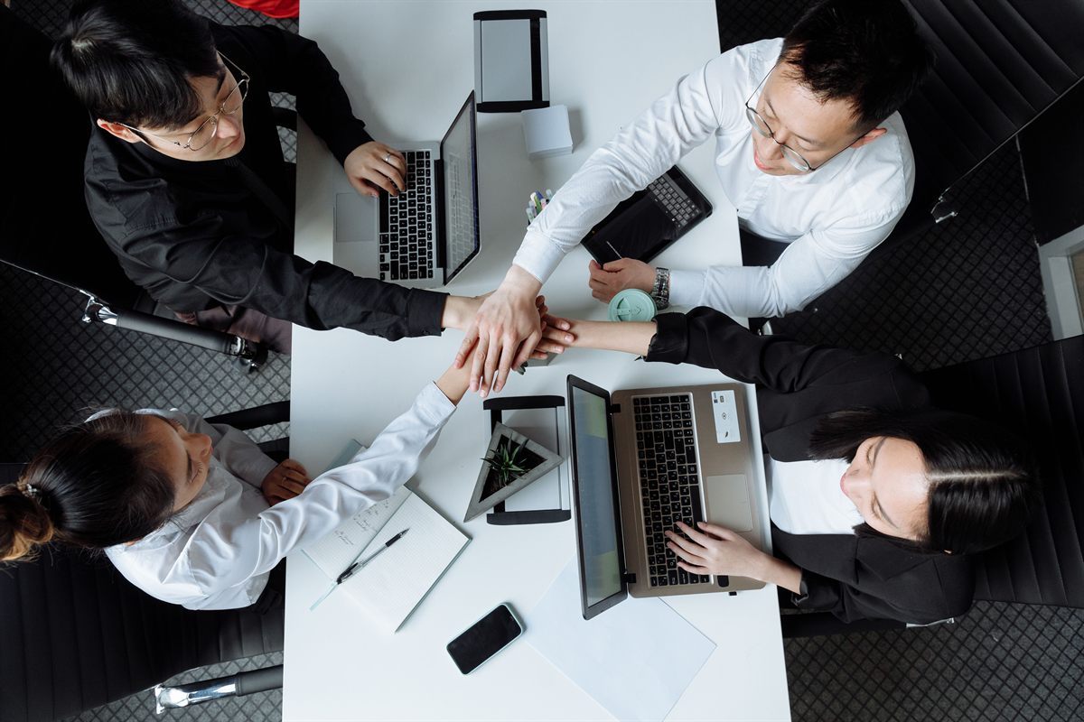 A team joining hands over a meeting table