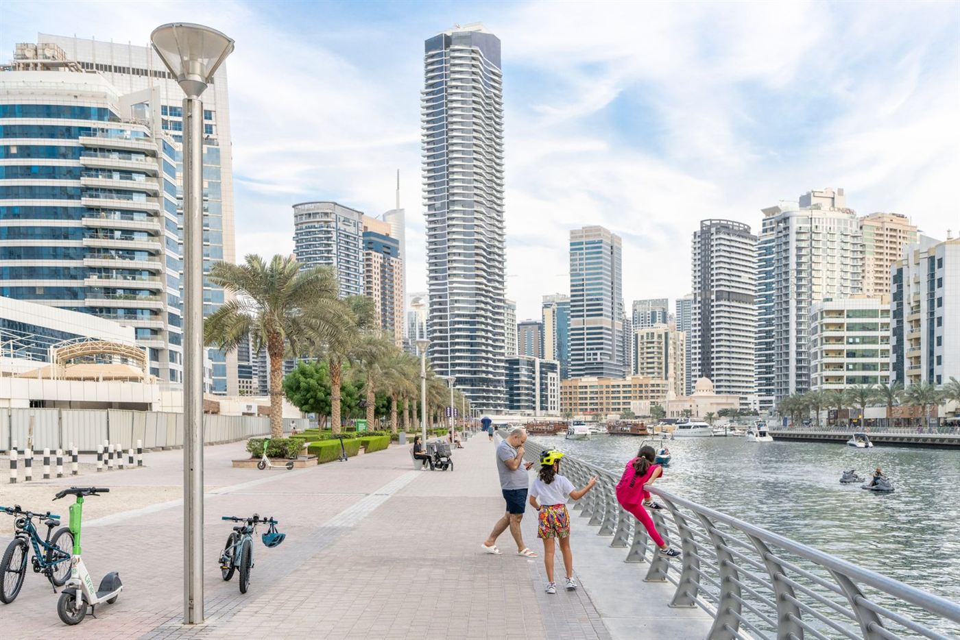 A father walking with his daughters on the Dubai Marina promenade